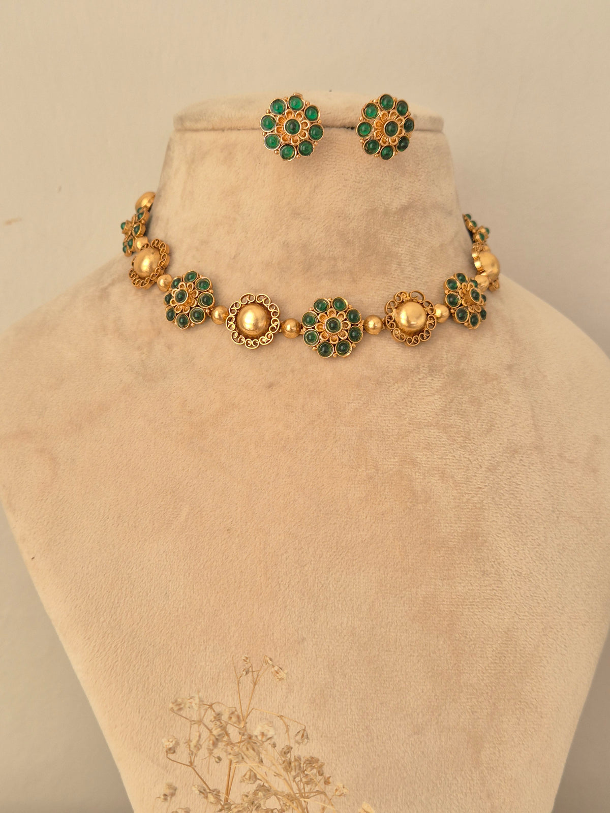 Gaurika gold choker necklace set with green stone floral motifs and matching earrings