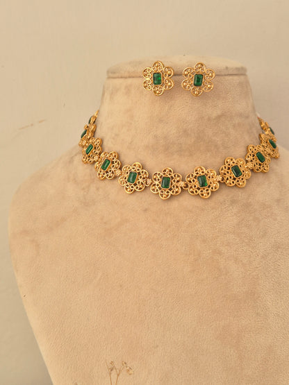 Gold-finish choker necklace with delicate floral filigree segments, each set with a rectangular green center stone, paired with matching stud earrings