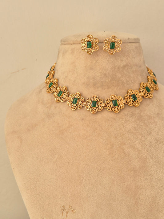 Gold-finish choker necklace with delicate floral filigree segments, each set with a rectangular green center stone, paired with matching stud earrings