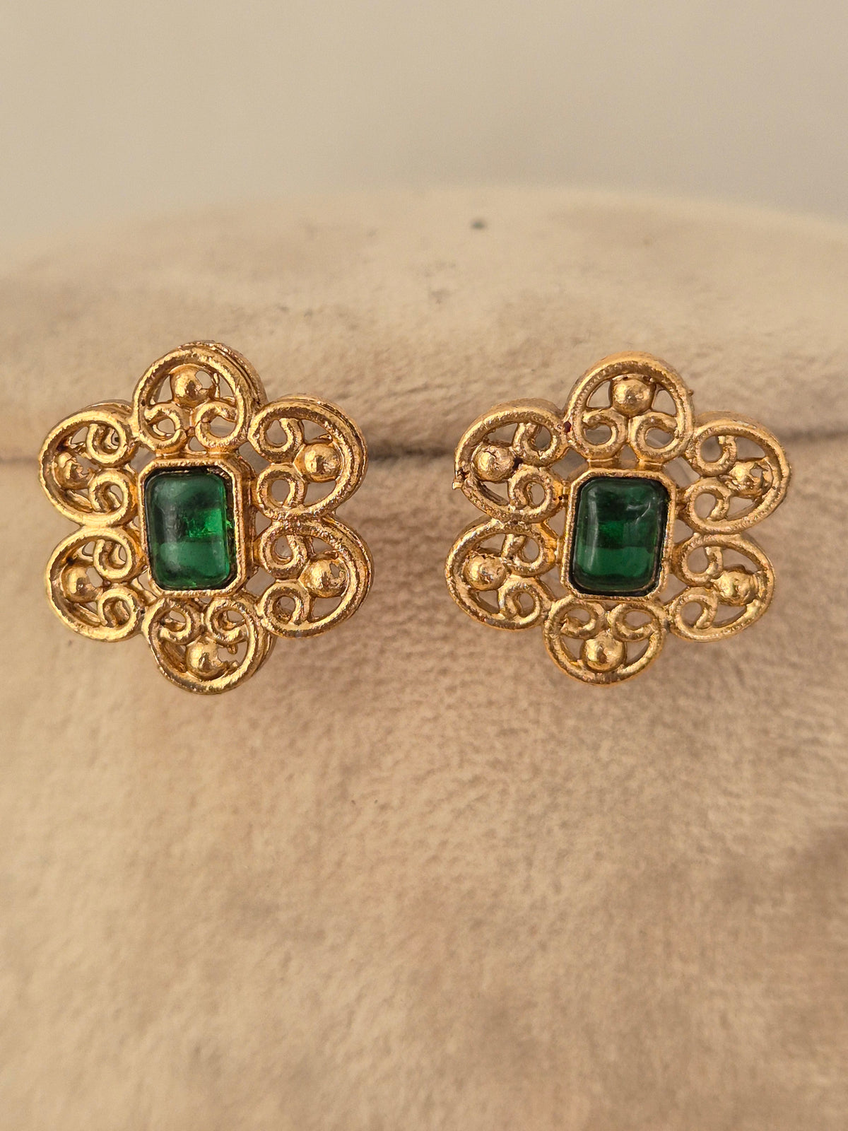 Ethnic gold floral stud earrings featuring green stone centers