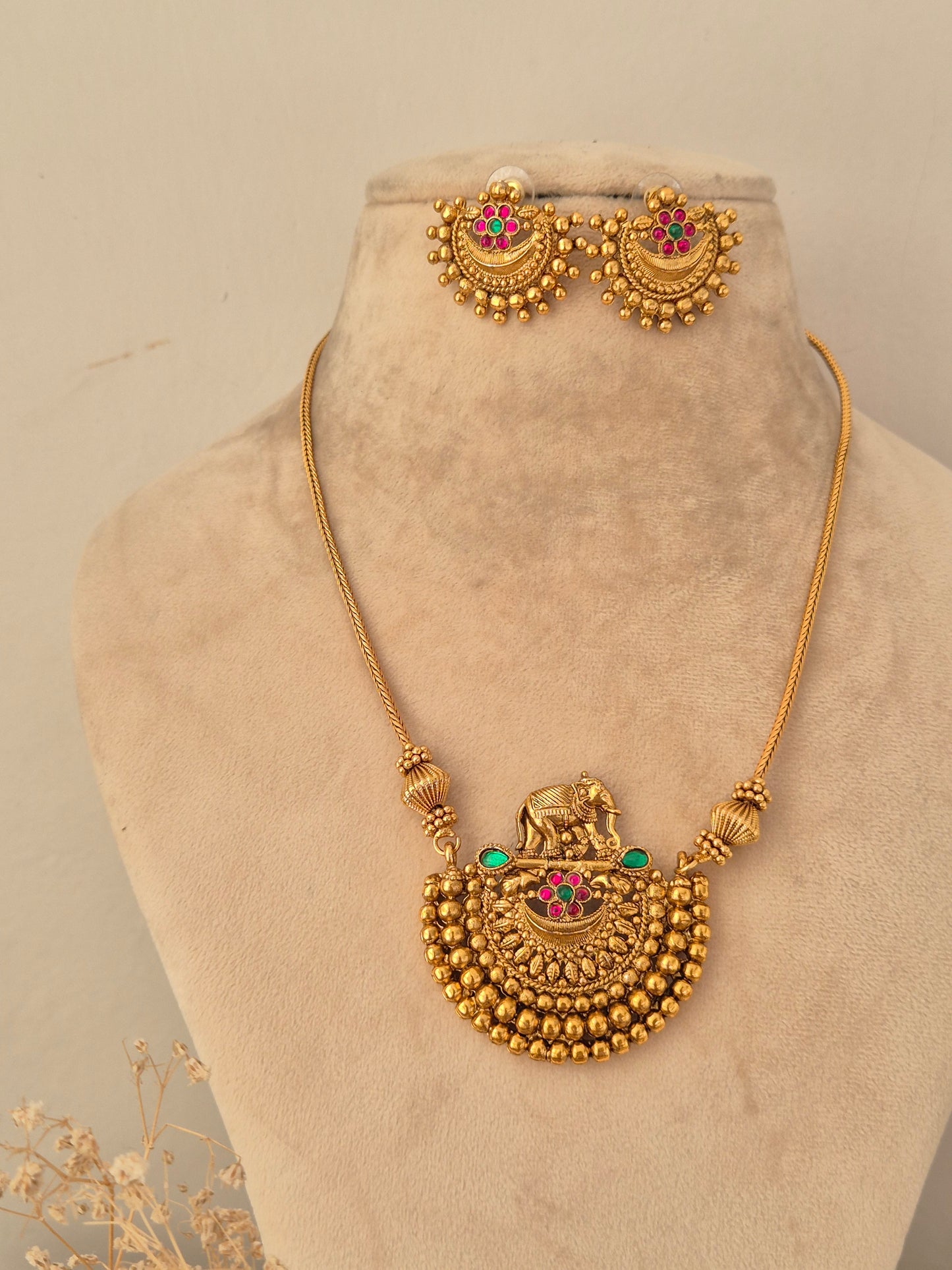 Traditional gold elephant motif pendant necklace set with pink and green stone accents