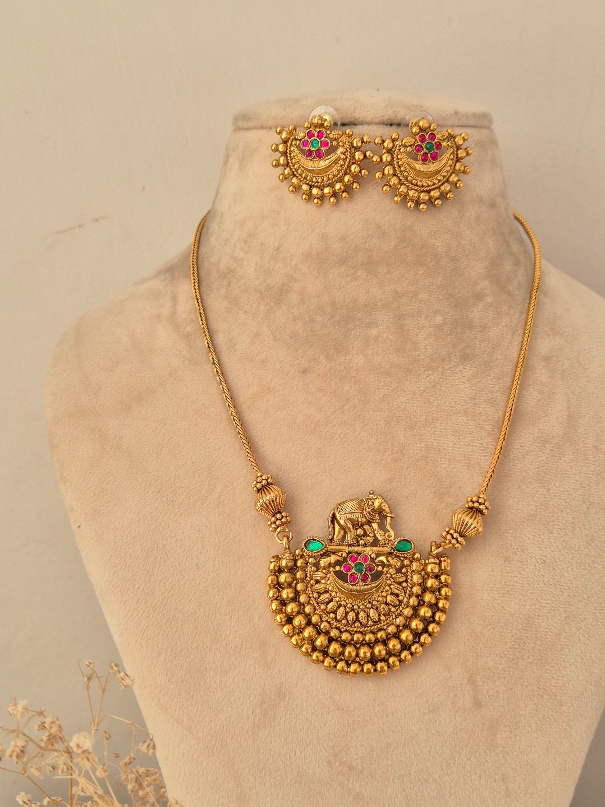 Traditional gold elephant motif pendant necklace set with pink and green stone accents