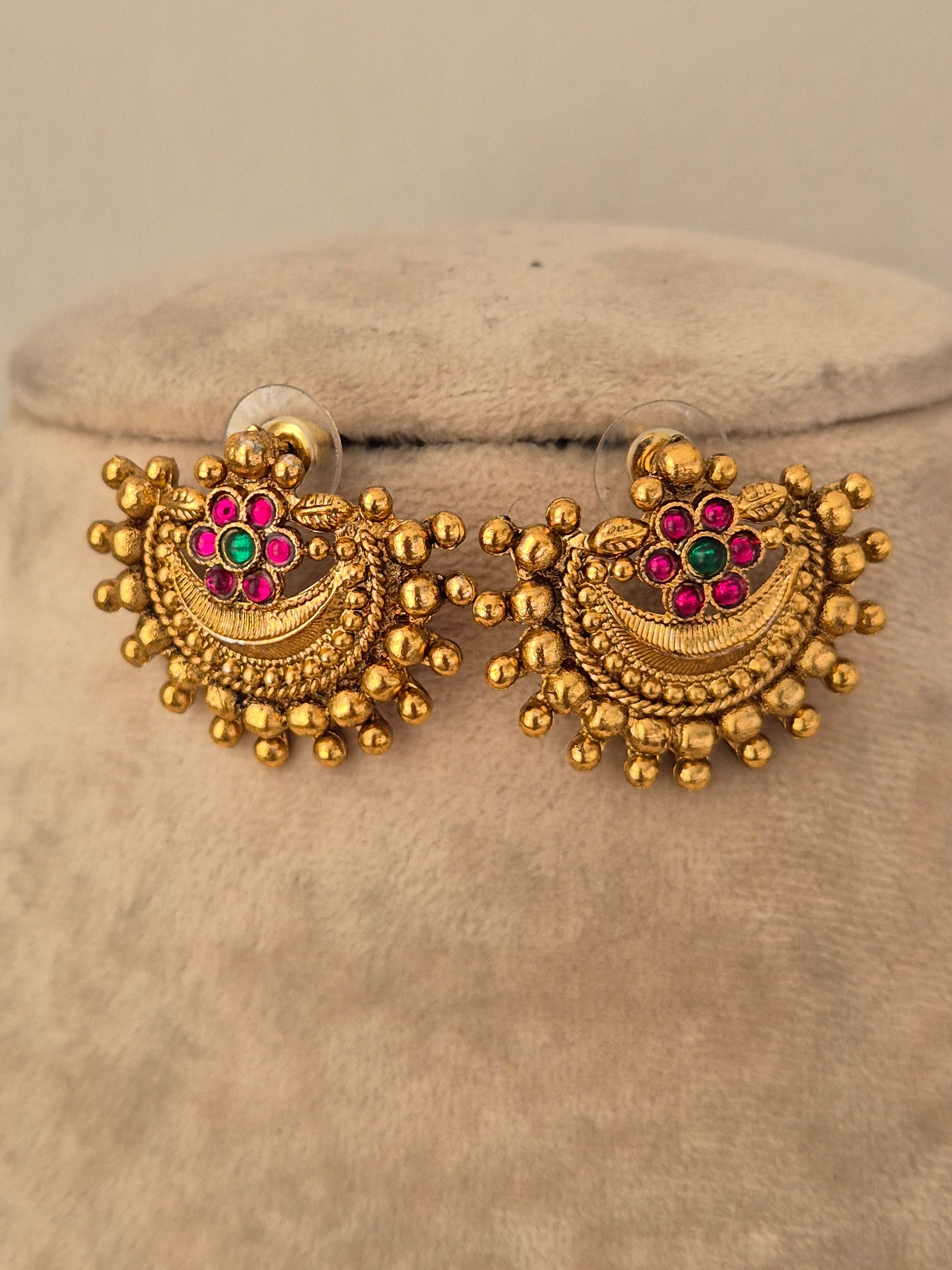 Antique gold-toned crescent stud earrings featuring textured bead trim and central pink and green stone flowers