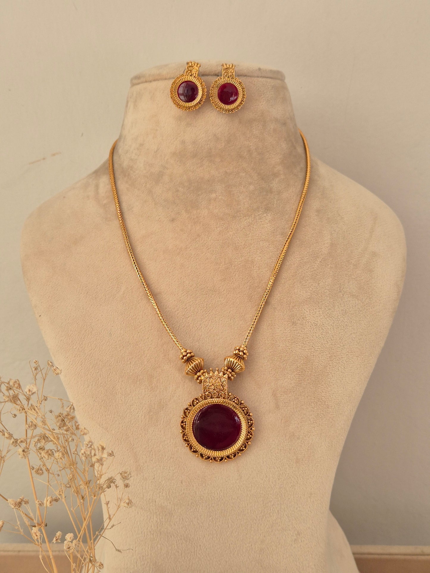 Antique gold-toned Yogisha chain necklace set featuring a round deep red gemstone pendant with ornate border details