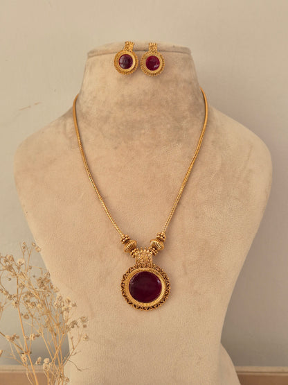 Antique gold-toned Yogisha chain necklace set featuring a round deep red gemstone pendant with ornate border details