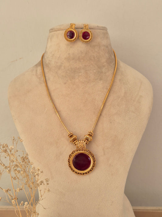 Antique gold-toned Yogisha chain necklace set featuring a round deep red gemstone pendant with ornate border details