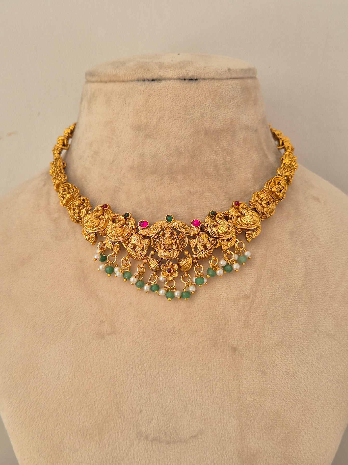 Naitri Waraya Necklace Set crafted in gold-toned brass alloy with traditional temple design work and green stone accents.