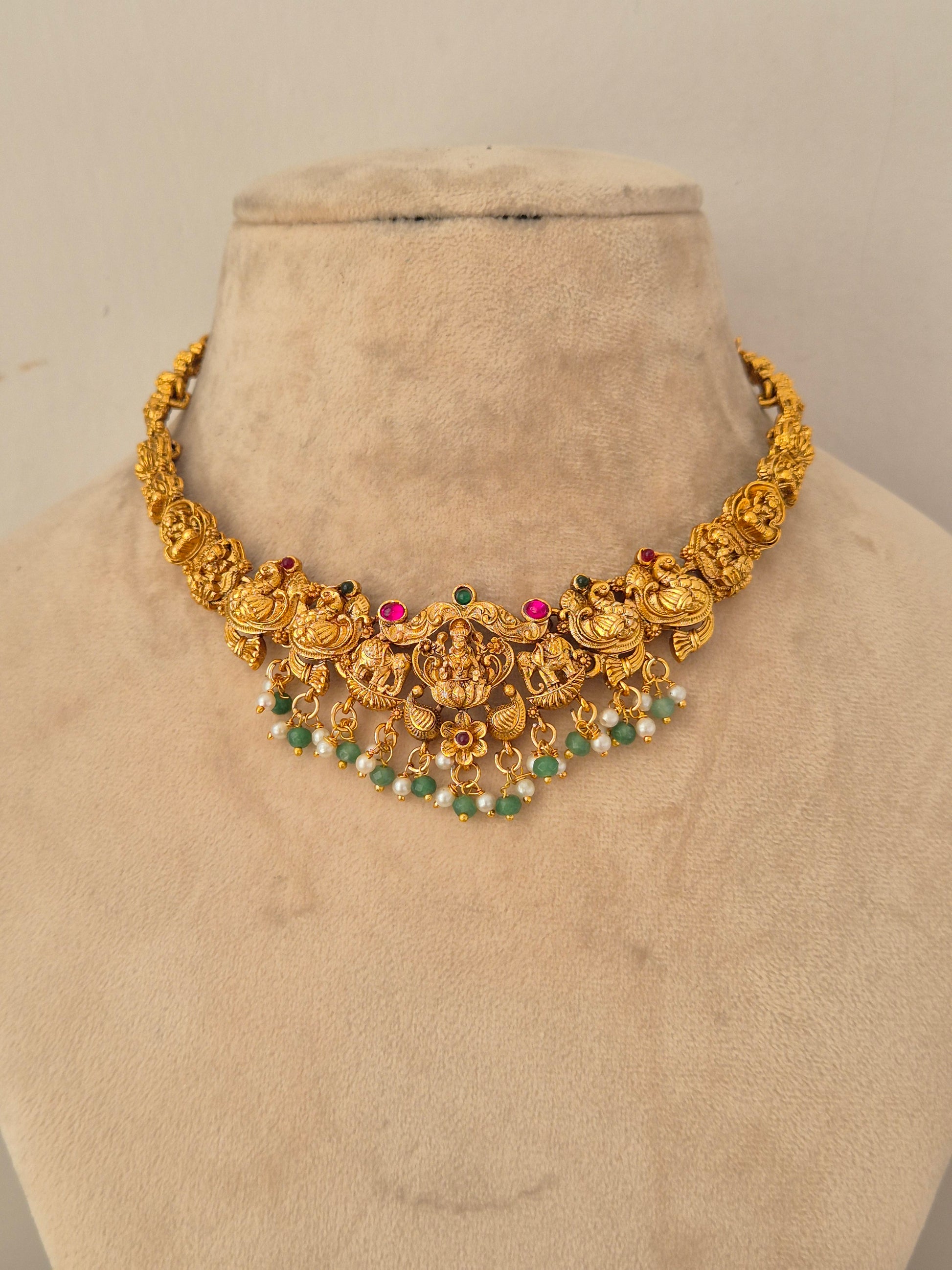 Naitri Waraya Necklace Set crafted in gold-toned brass alloy with traditional temple design work and green stone accents.
