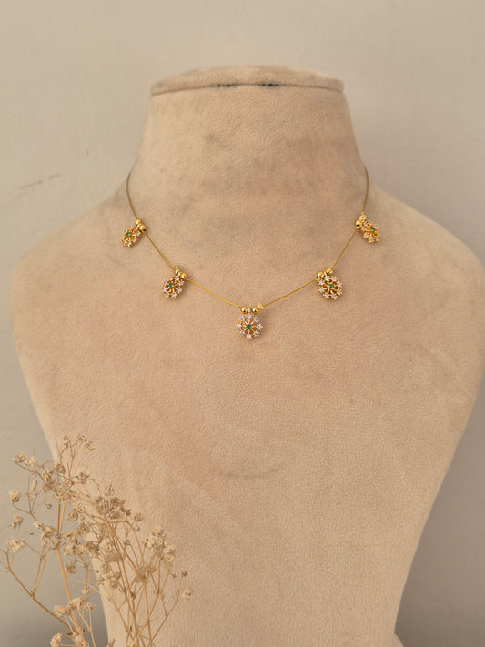 Descriptive & SEO-focused: Gold-finish invisible chain necklace featuring five floral stone-studded motifs with subtle green accents