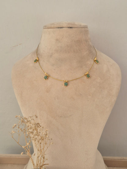 Gold-toned Chetika invisible chain necklace featuring five small green stone floral charms