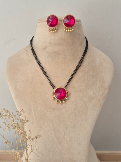 Pranati Mangalsutra Set – Multi-strand black beaded chain with a large round magenta stone pendant and matching round pink stud earrings