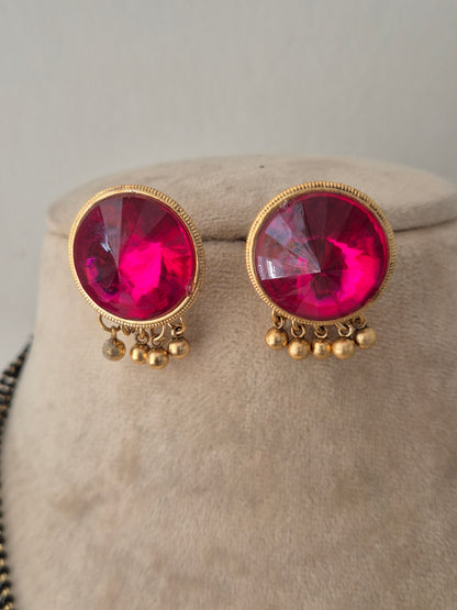 Pranati Mangalsutra Set – Pair of round magenta pink gemstone stud earrings with gold beaded drop fringe accents, displayed on a neutral fabric bust