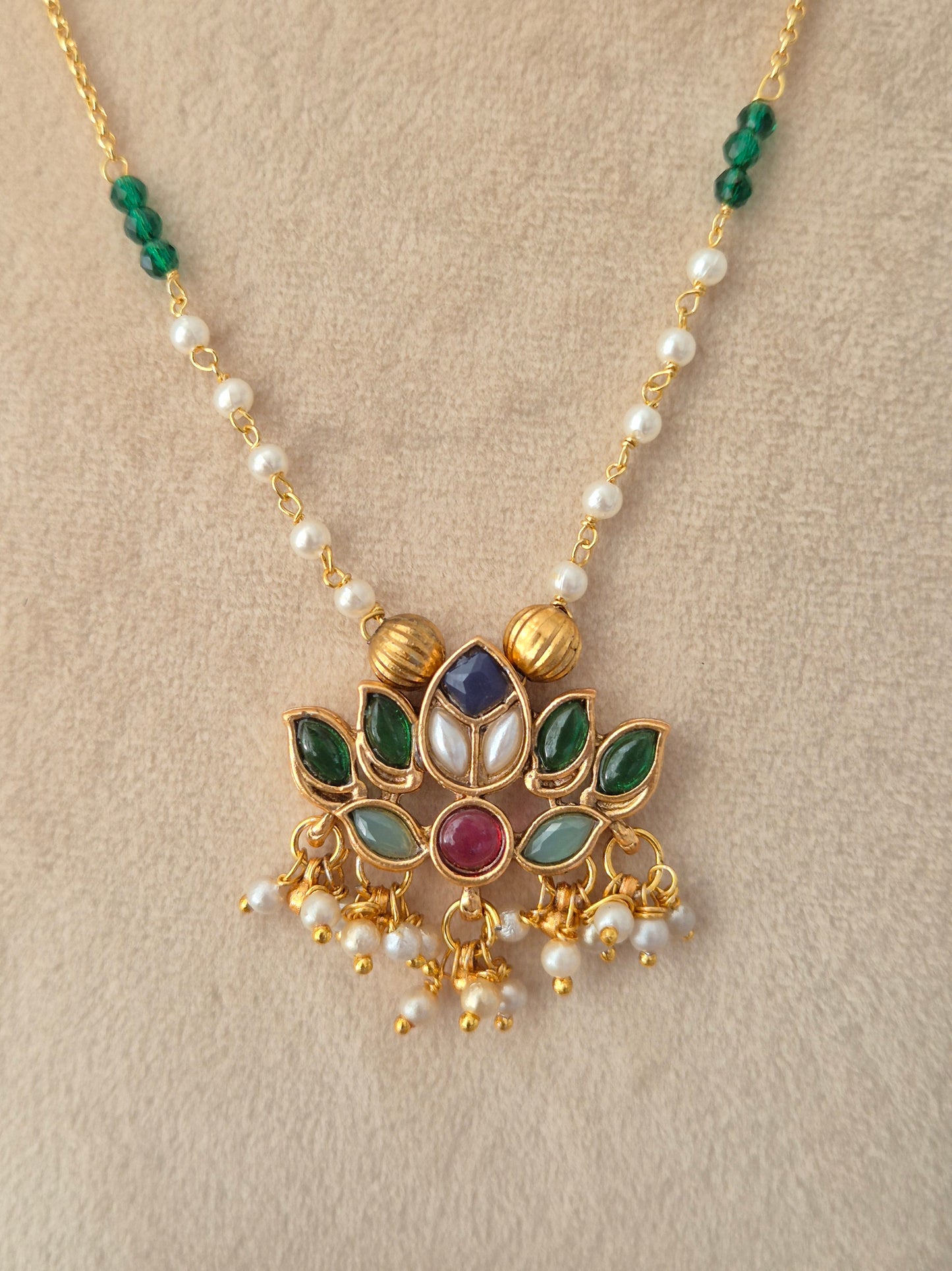 Luvina Necklace Set – Close-up view of a gold chain necklace featuring green and pearl bead accents, with a central lotus-shaped kundan pendant studded with multi-colored stones and dangling pearl drops