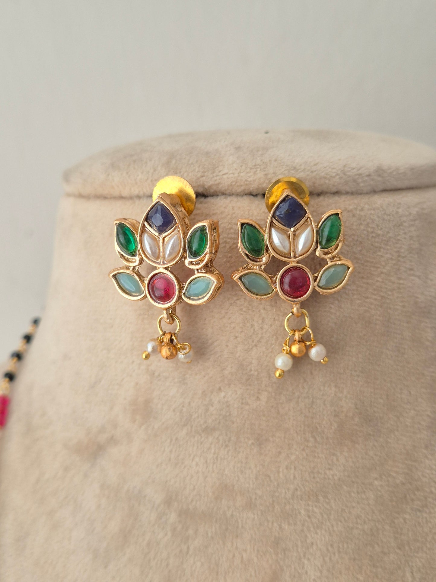 Pair of floral lotus-shaped kundan stud earrings featuring multi-colored gemstones and dangling pearl drops