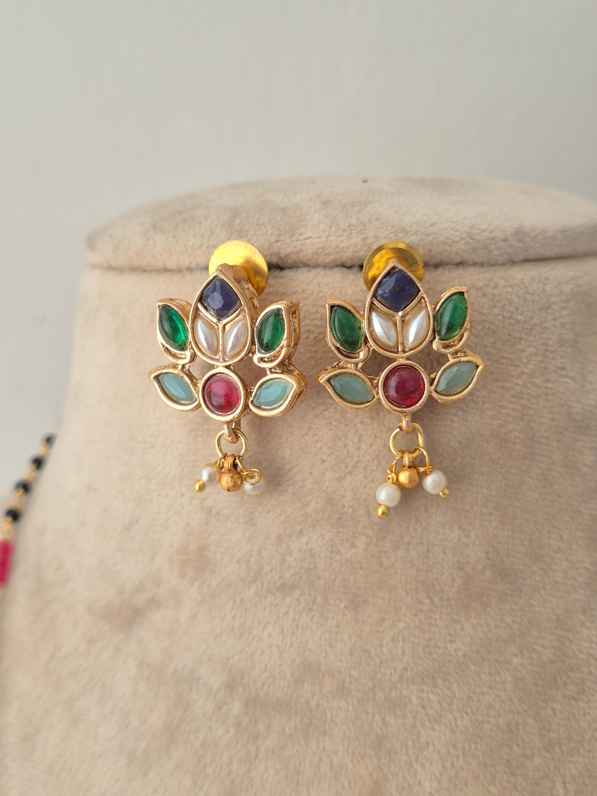 Pair of floral lotus-shaped kundan stud earrings featuring multi-colored gemstones and dangling pearl drops