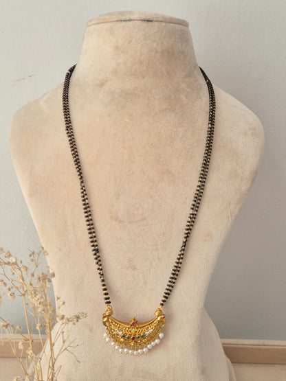 Traditional black-beaded Padmini Mangalsutra featuring a gold crescent pendant embellished with red and green stones and tiny pearl drops