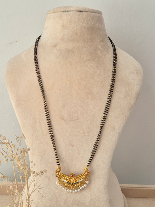 Traditional black-beaded Padmini Mangalsutra featuring a gold crescent pendant embellished with red and green stones and tiny pearl drops