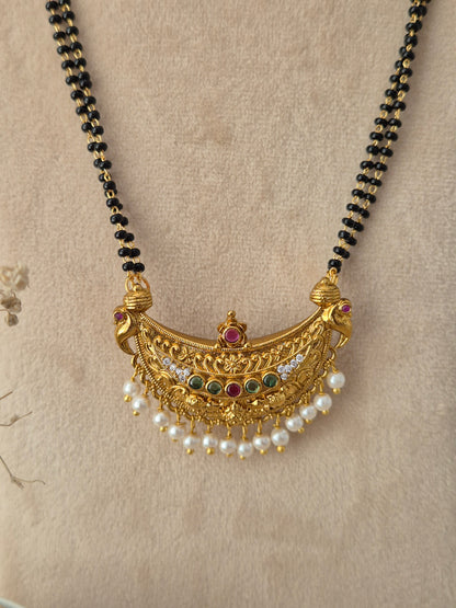 
Traditional gold Padmini Mangalsutra with a crescent pendant, stone embellishments, white pearl drops, and black-beaded chain