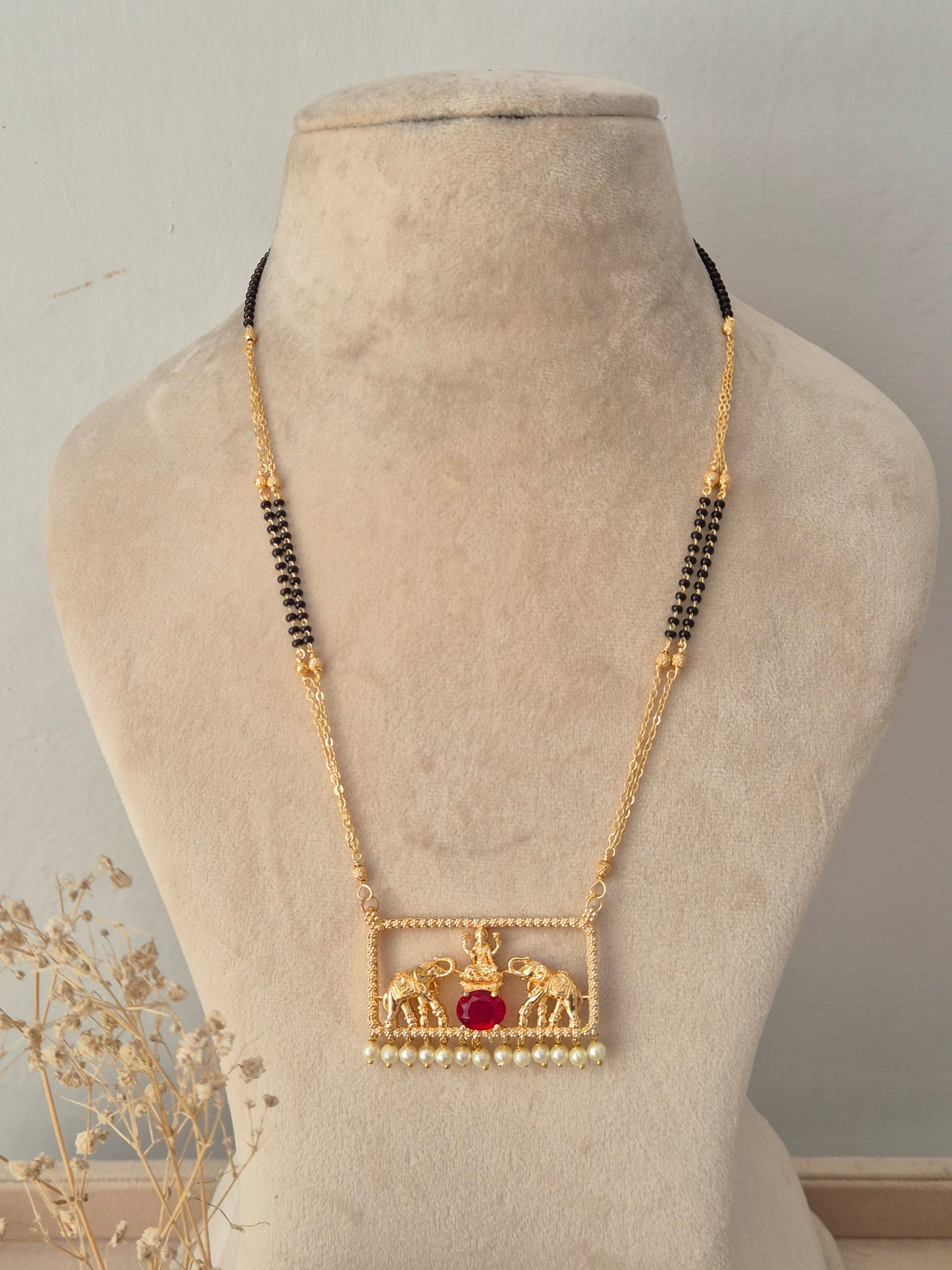 Traditional gold Jivinta Mangalsutra with an ornate rectangular elephant motif pendant, red stone, pearl drops, and black-beaded chain
