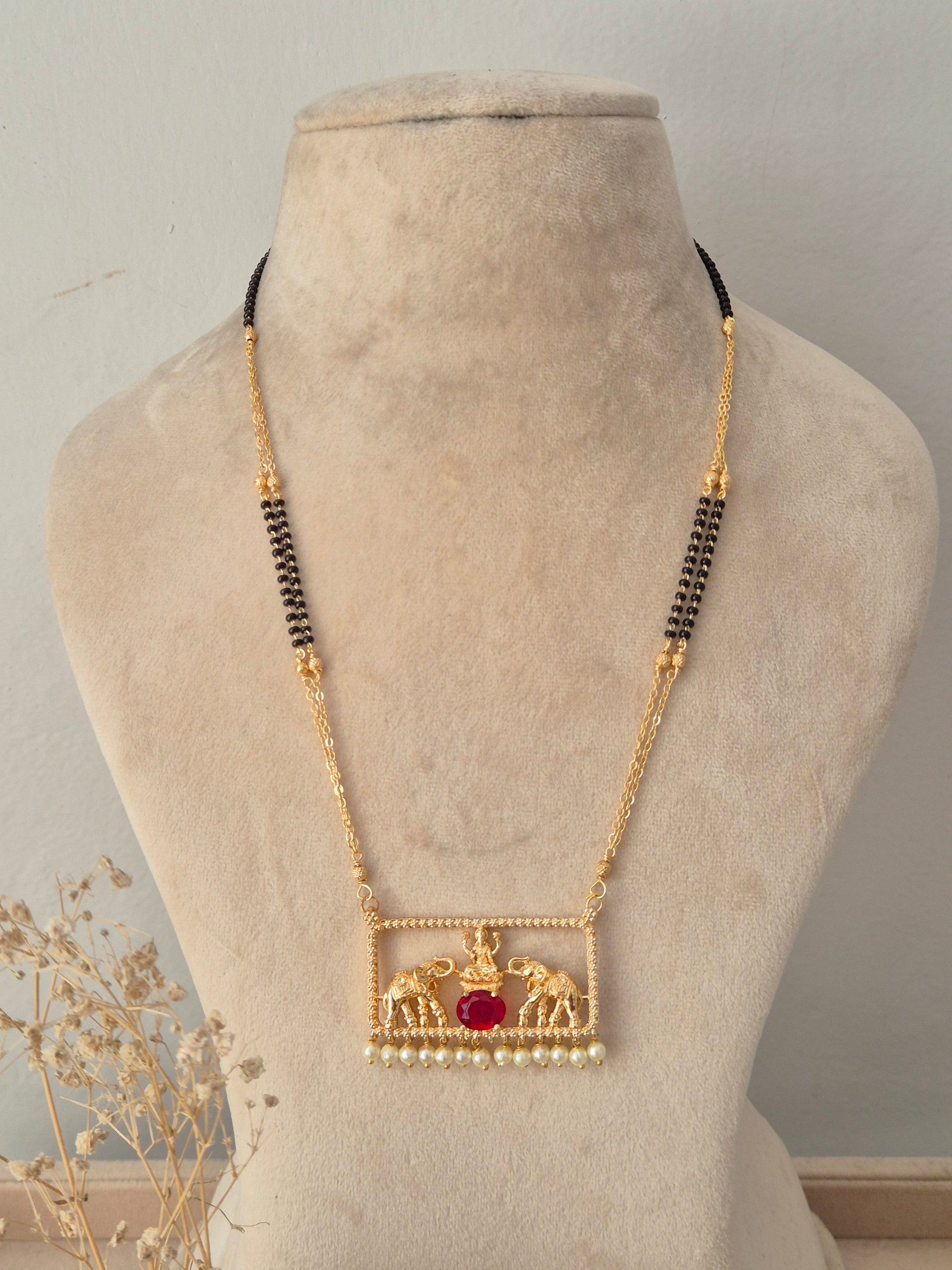 Traditional gold Jivinta Mangalsutra with an ornate rectangular elephant motif pendant, red stone, pearl drops, and black-beaded chain