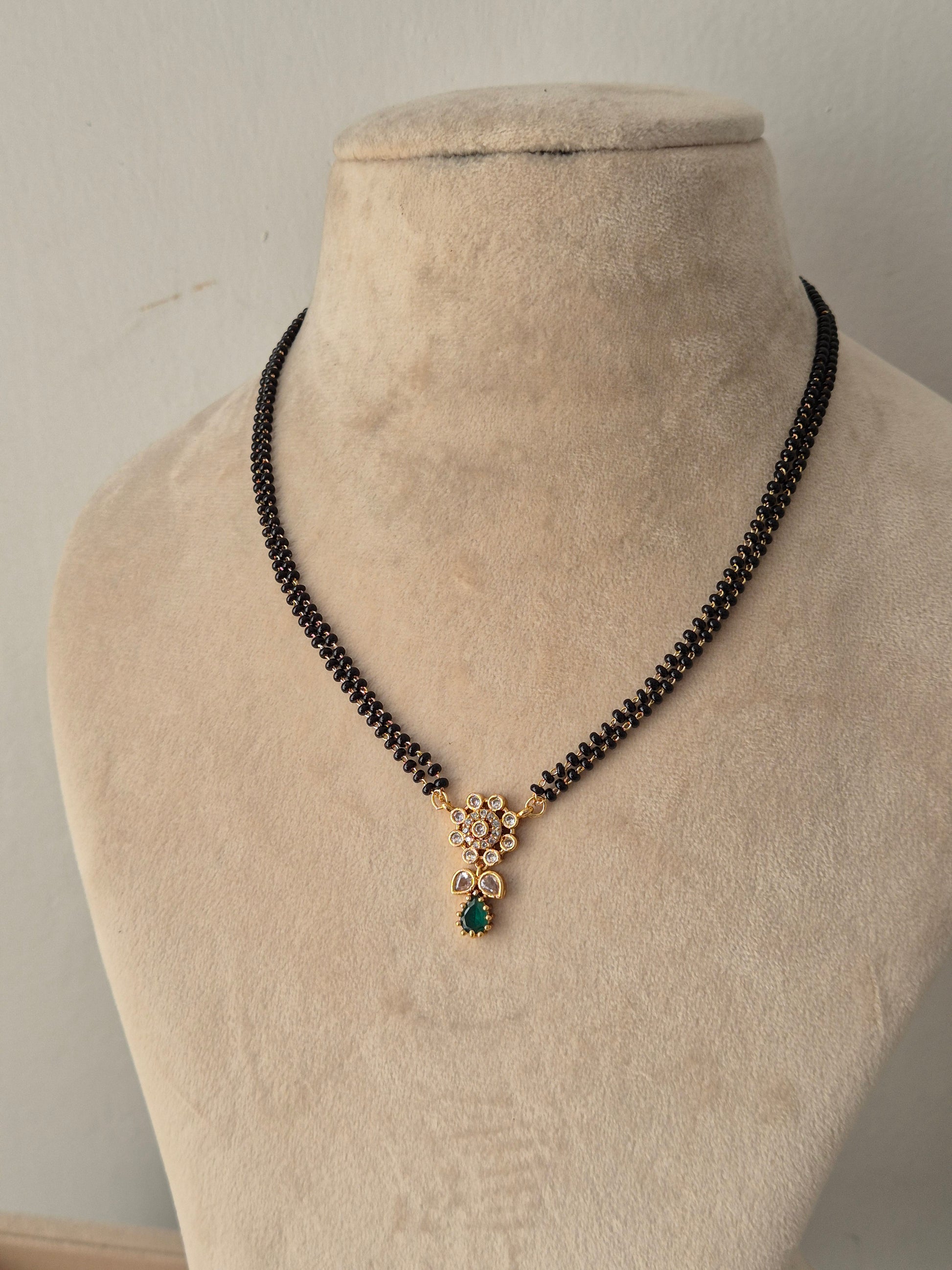 Traditional Balaka Mangalsutra with a gold floral pendant, green teardrop stone drop, and double-strand black beads chain
