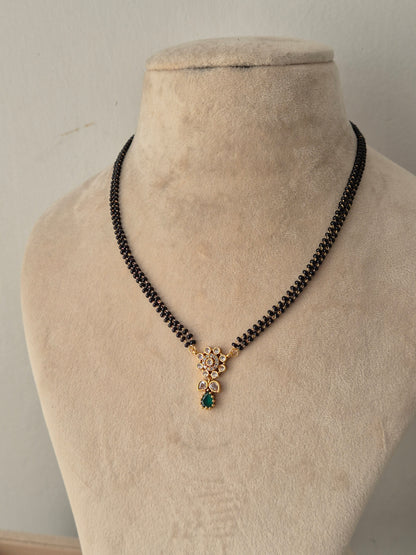 Traditional Balaka Mangalsutra with a gold floral pendant, green teardrop stone drop, and double-strand black beads chain
