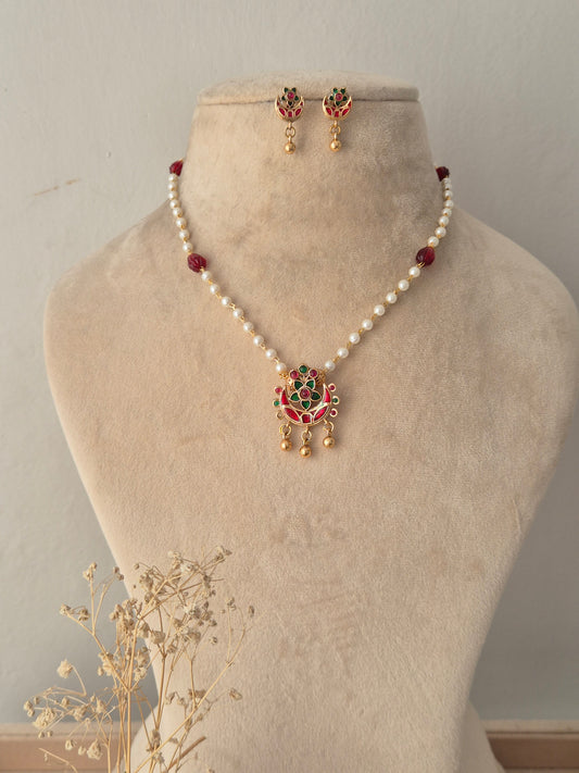Aloka Necklace Set featuring a white pearl beaded chain with a red and green stone gold pendant and matching drop earrings