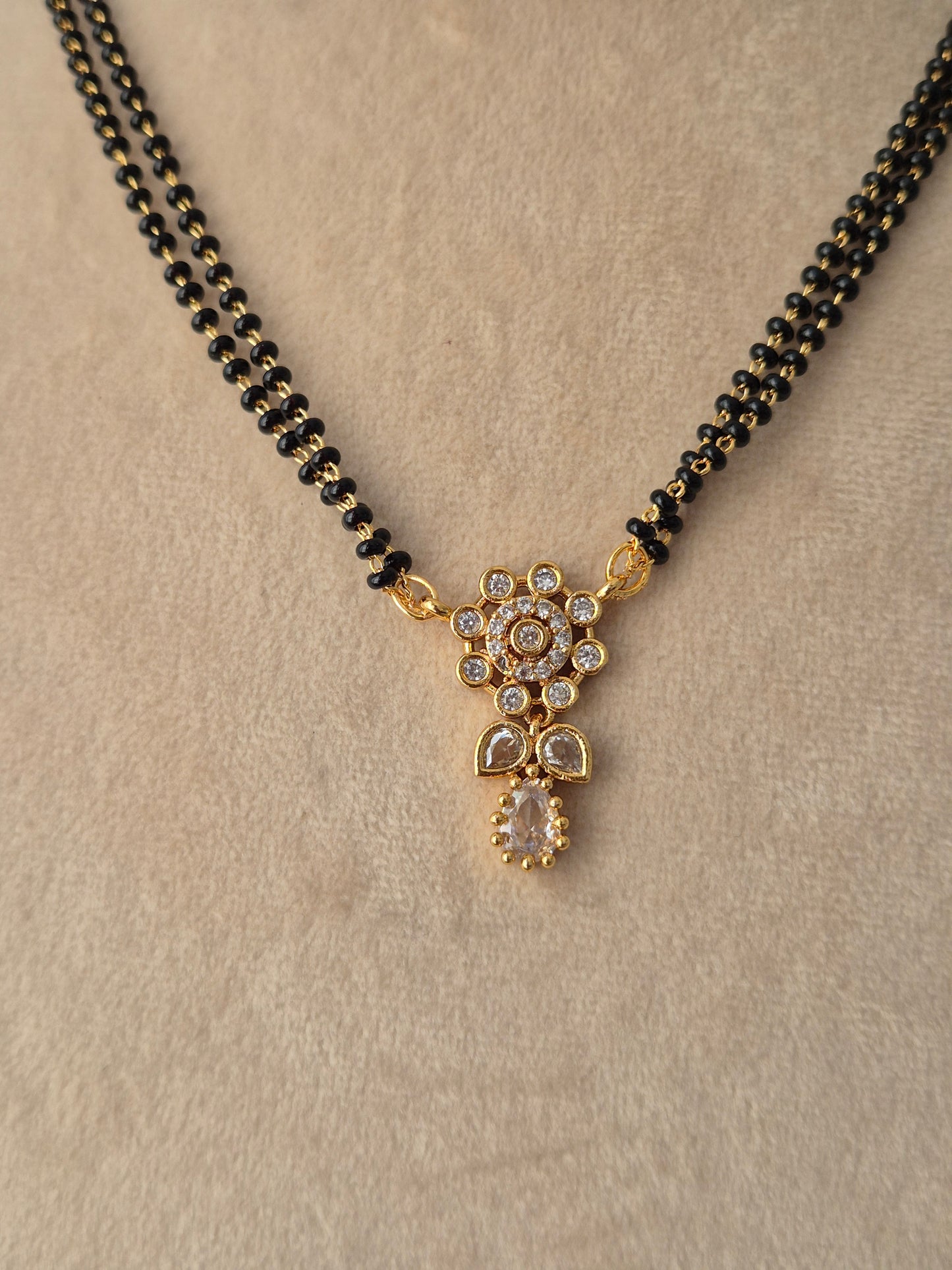 Close-up view of the Chetasi Mangalsutra gold floral CZ pendant with a teardrop drop and black-beaded chain