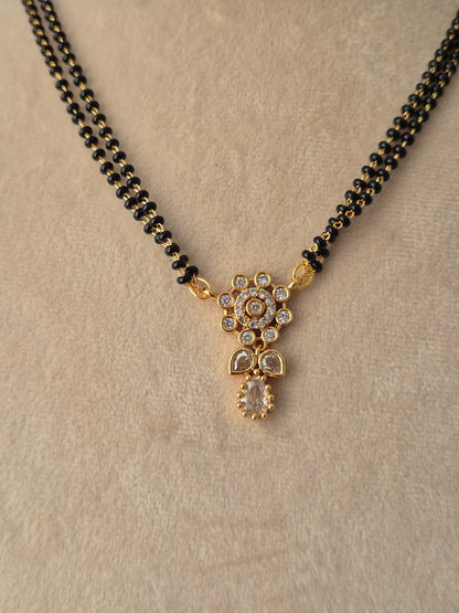 Close-up view of the Chetasi Mangalsutra gold floral CZ pendant with a teardrop drop and black-beaded chain