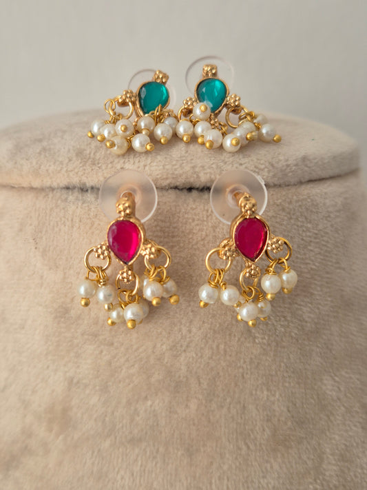 Reversible gold-toned stud earrings featuring teardrop pink stones on one side and green stones on the reverse, bordered by dangling pearl bead clusters