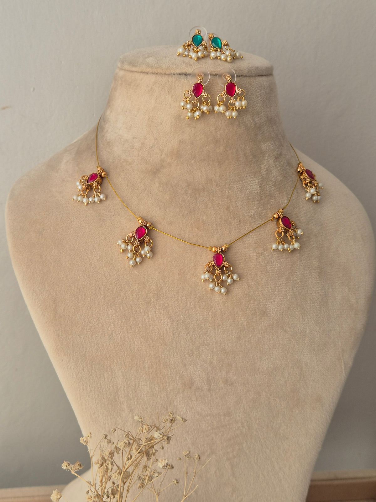 Reversible Ari invisible chain necklace featuring green teardrop stone motifs with pearl clusters, displayed on a jewelry mannequin with both pink and green sides of matching earrings
