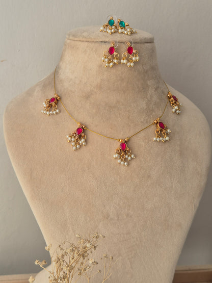 Reversible Ari invisible chain necklace featuring green teardrop stone motifs with pearl clusters, displayed on a jewelry mannequin with both pink and green sides of matching earrings