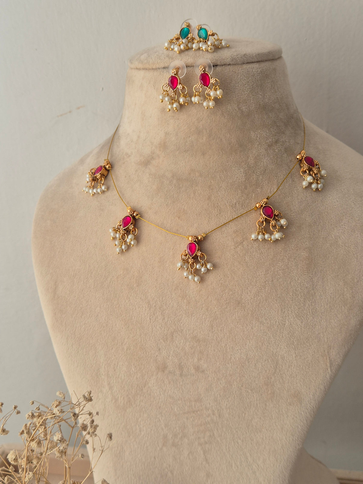 Delicate gold-toned invisible chain necklace set with green teardrop stones and hanging pearl drops