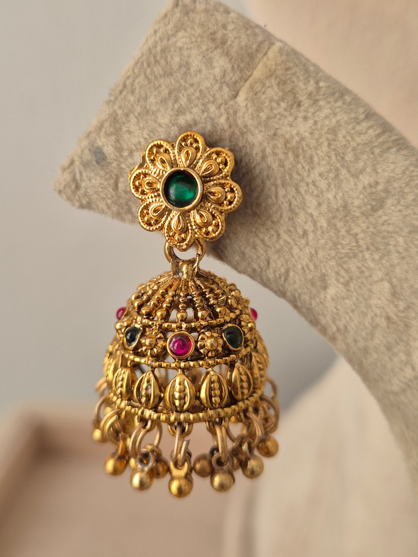 
Antique gold jhumka earring with a green floral stud top, pink and green stones, and dangling gold beads from the Alpana Choker Necklace Set