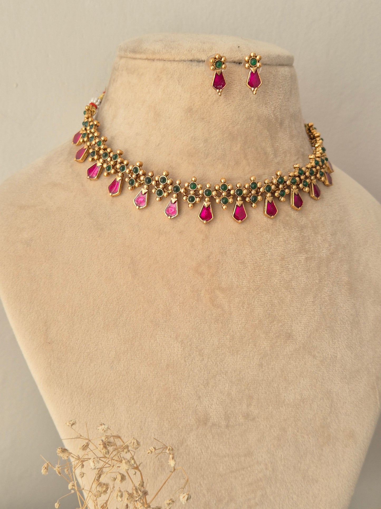 Jamini Necklace Set showcasing a gold-toned choker necklace embellished with small green beads and hanging pink teardrop stones, paired with matching pink teardrop drop earrings