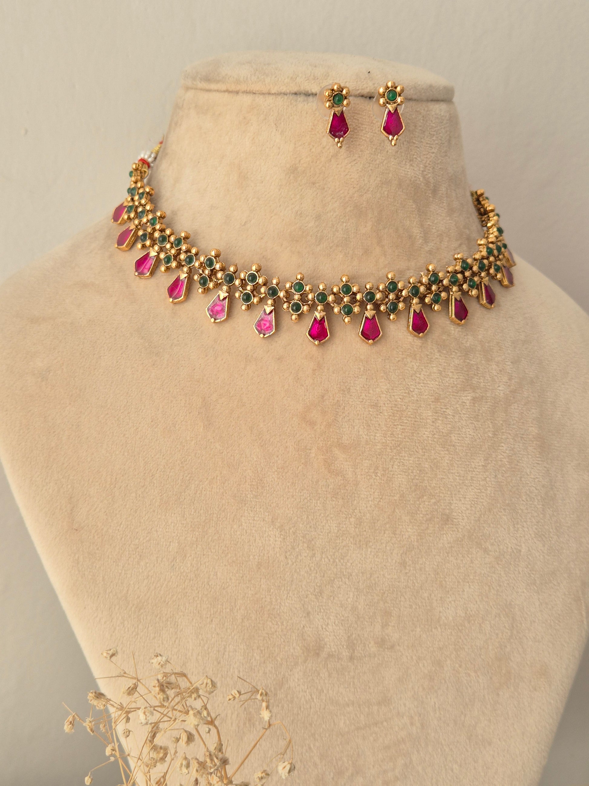 Jamini Necklace Set showcasing a gold-toned choker necklace embellished with small green beads and hanging pink teardrop stones, paired with matching pink teardrop drop earrings