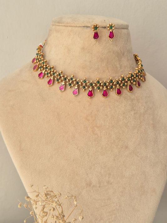 Jamini Necklace Set showcasing a gold-toned choker necklace embellished with small green beads and hanging pink teardrop stones, paired with matching pink teardrop drop earrings