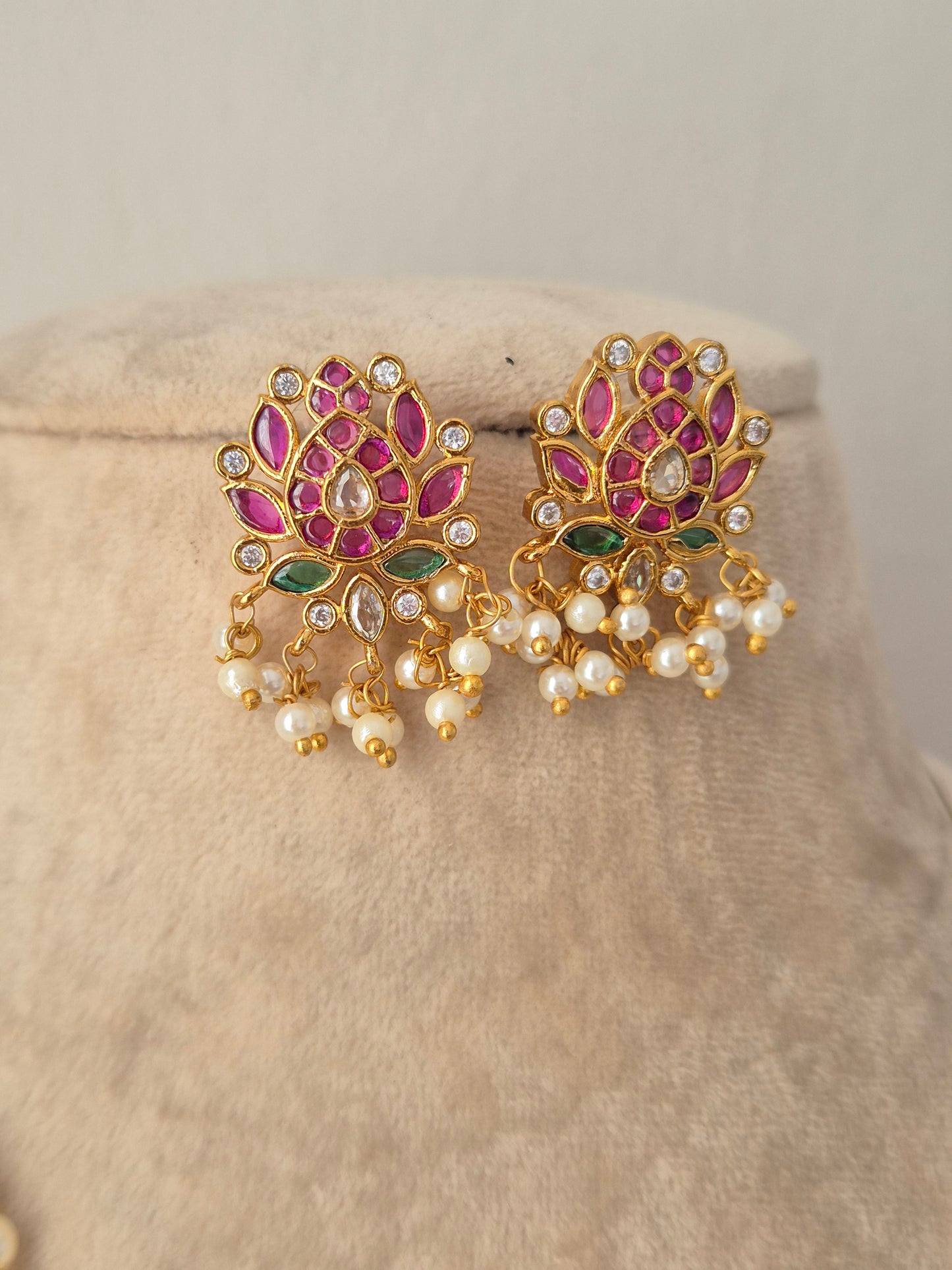 Pair of gold lotus-shaped stud earrings with pink stones, green accents, and pearl drops from the Ludhika Necklace Set