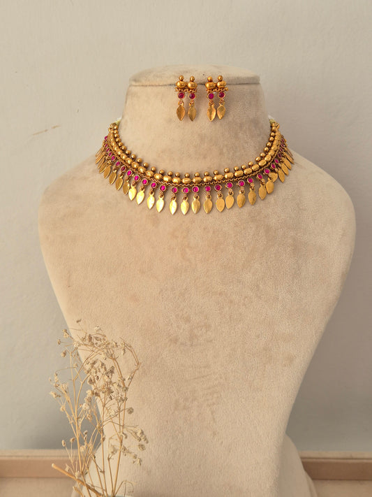 Pahal Necklace Set featuring a gold choker with pink stone accents and dangling leaf charms, paired with matching drop earrings