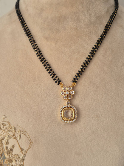 Close-up view of the Kavika Mangalsutra gold floral CZ pendant with a dangling teardrop accent and black bead chain