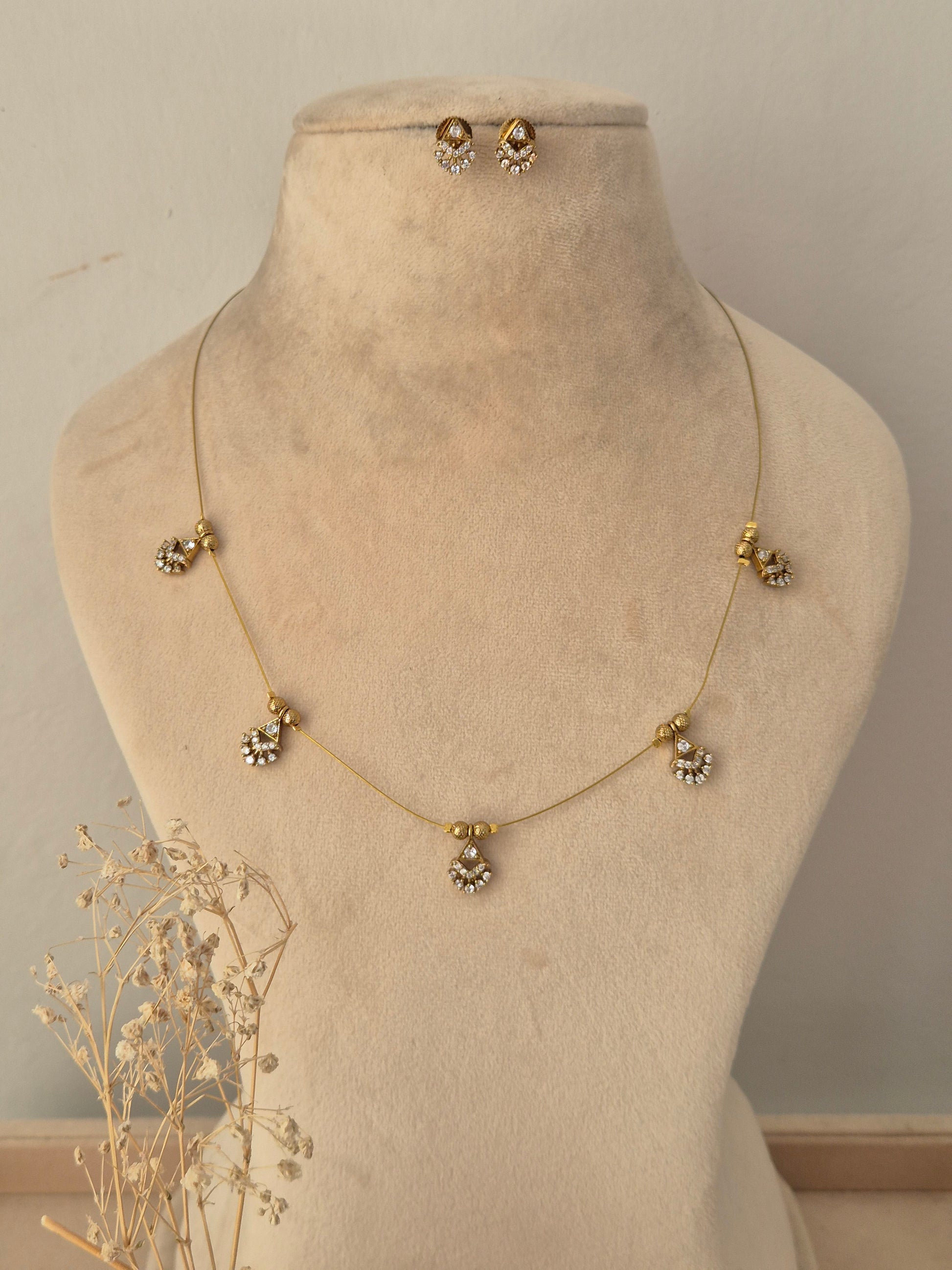 Ishrat Invisible Necklace Chain Set featuring a delicate gold-toned chain with five CZ charm pendants and matching stud earrings