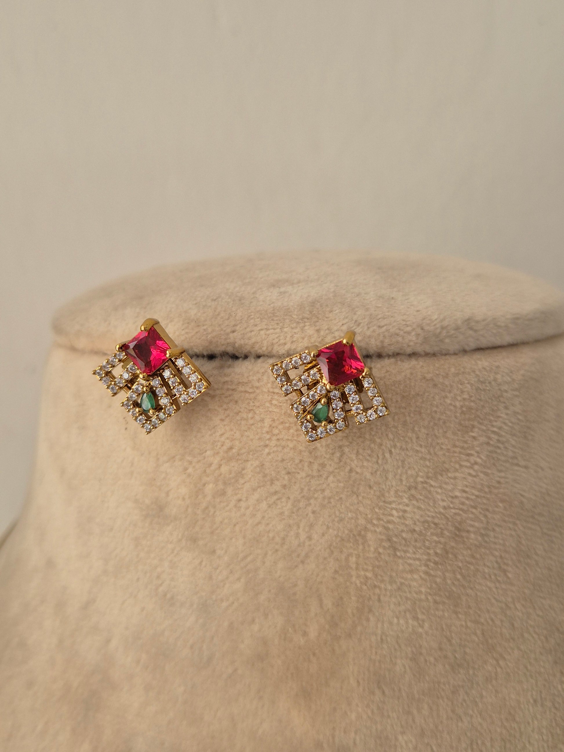 Pair of gold geometric stud earrings with red, green, and clear CZ stones matching the Labdhi Invisible Necklace Chain Set