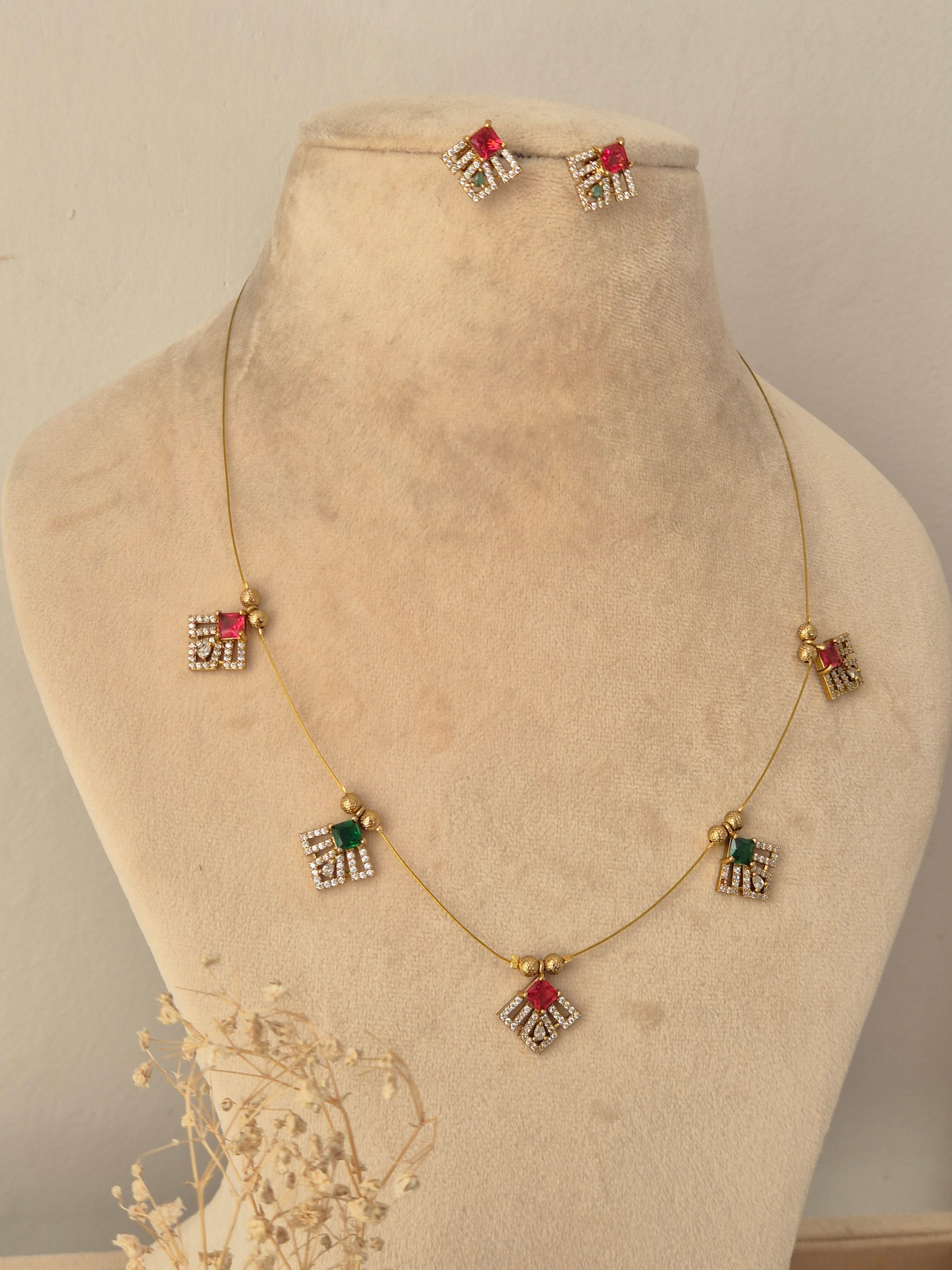 Labdhi Invisible Necklace Chain Set gold wire necklace with red and green CZ stone charms and matching stud earrings by Naitri