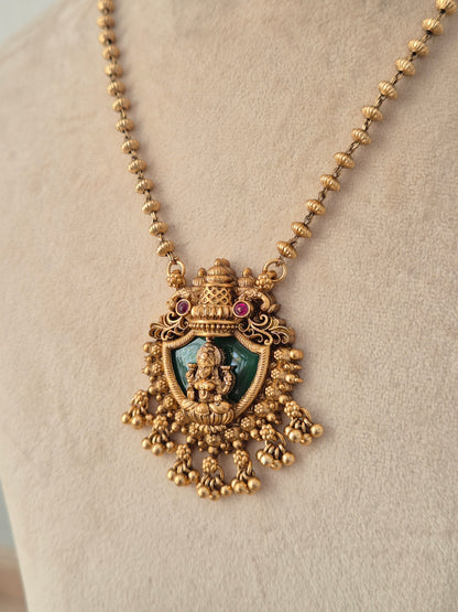 Charumati Necklace Set close-up view of antique gold temple pendant with green enamel Lakshmi motif by Naitri.