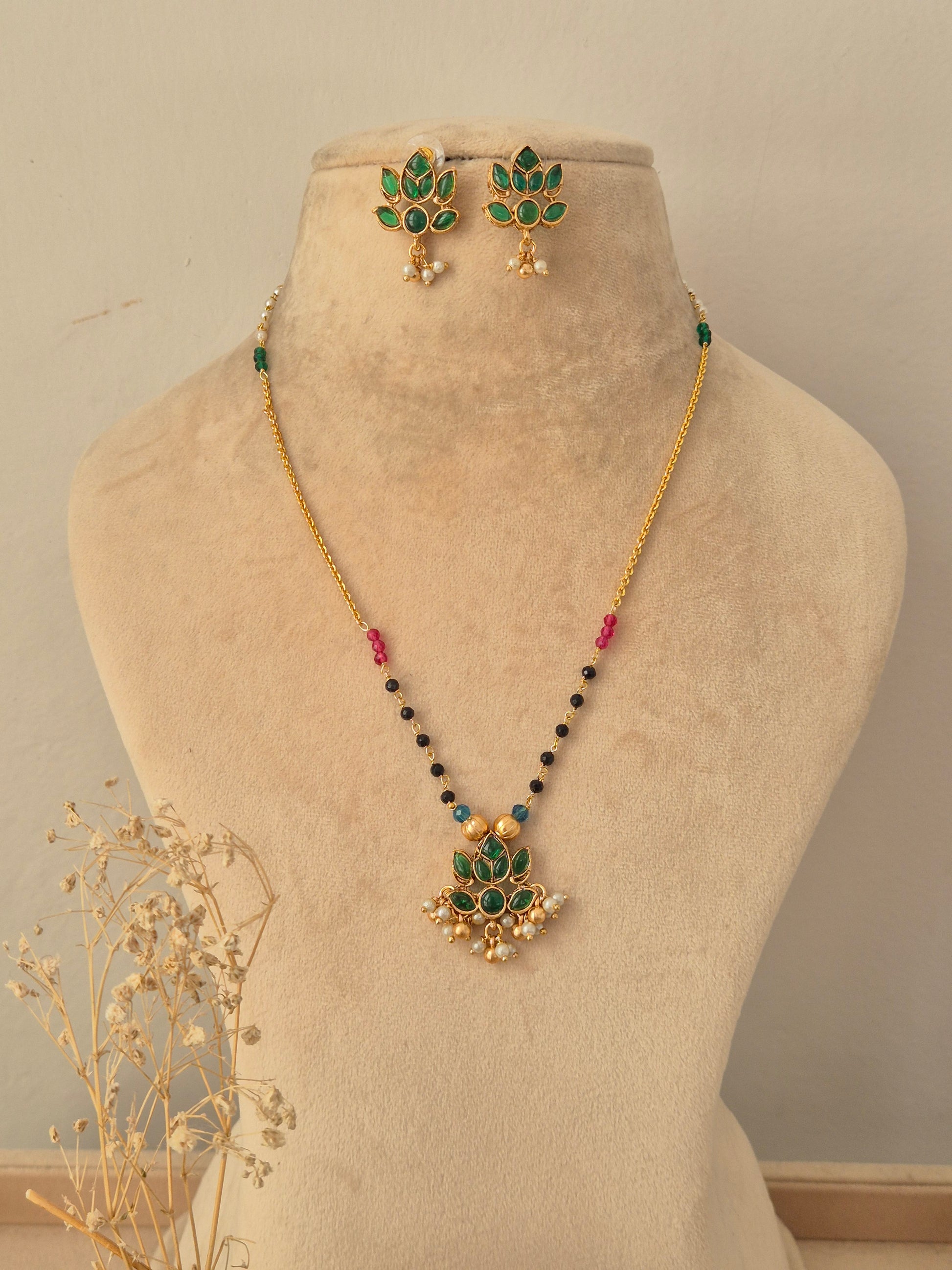 Prabhati Necklace Set featuring a gold chain with green stone lotus pendant, beaded accents, and matching earrings