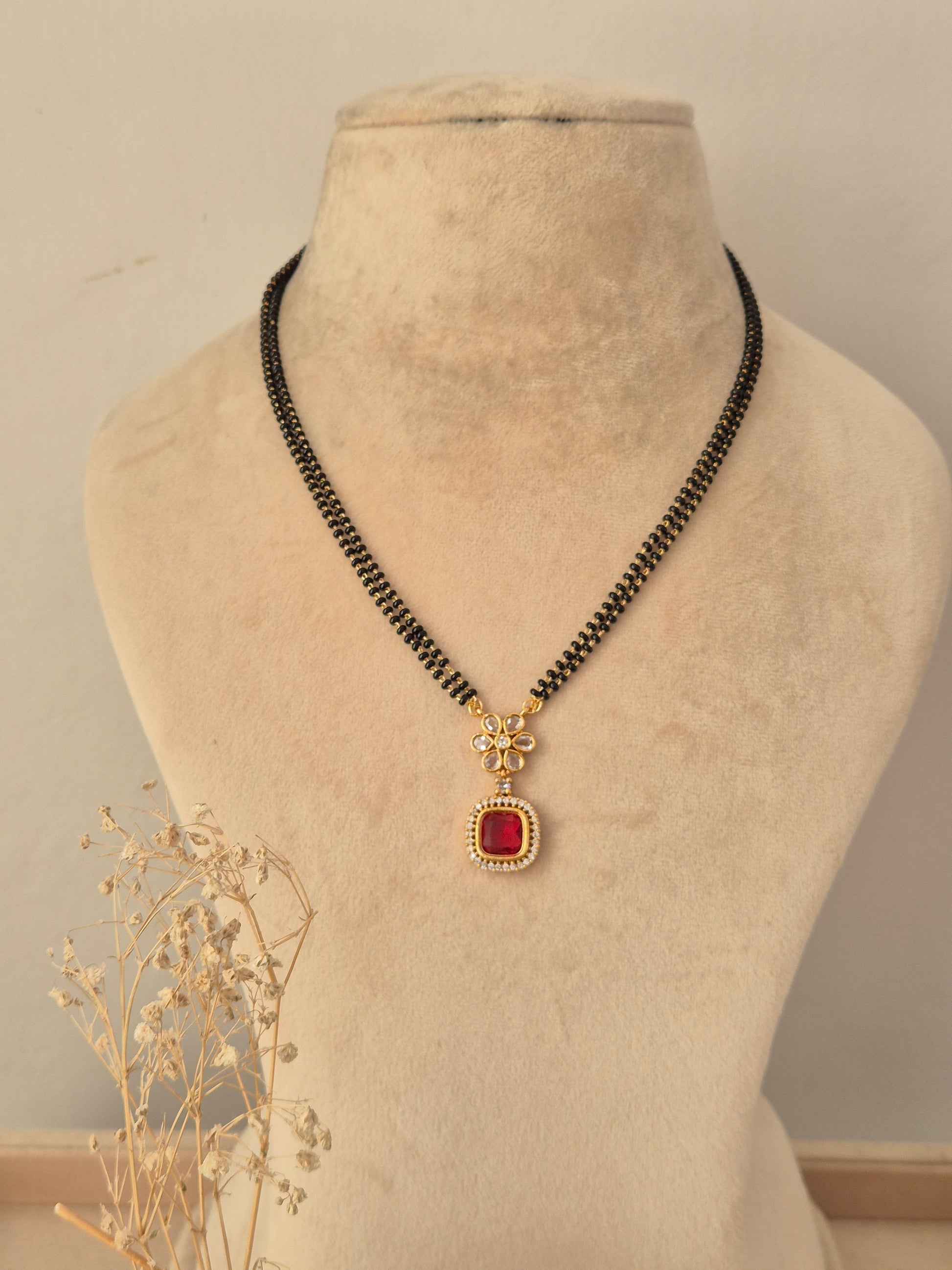Prisham Mangalsutra featuring a double-strand black bead chain with a gold pendant and red square stone