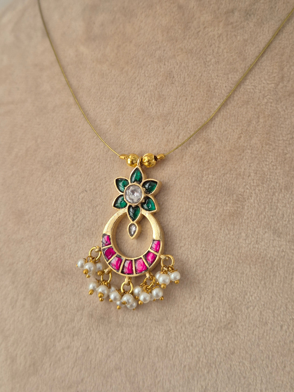 Detailed view of an antique gold choker necklace featuring ruby-pink teardrop stones, flower-motif dangles, and matching stud earrings