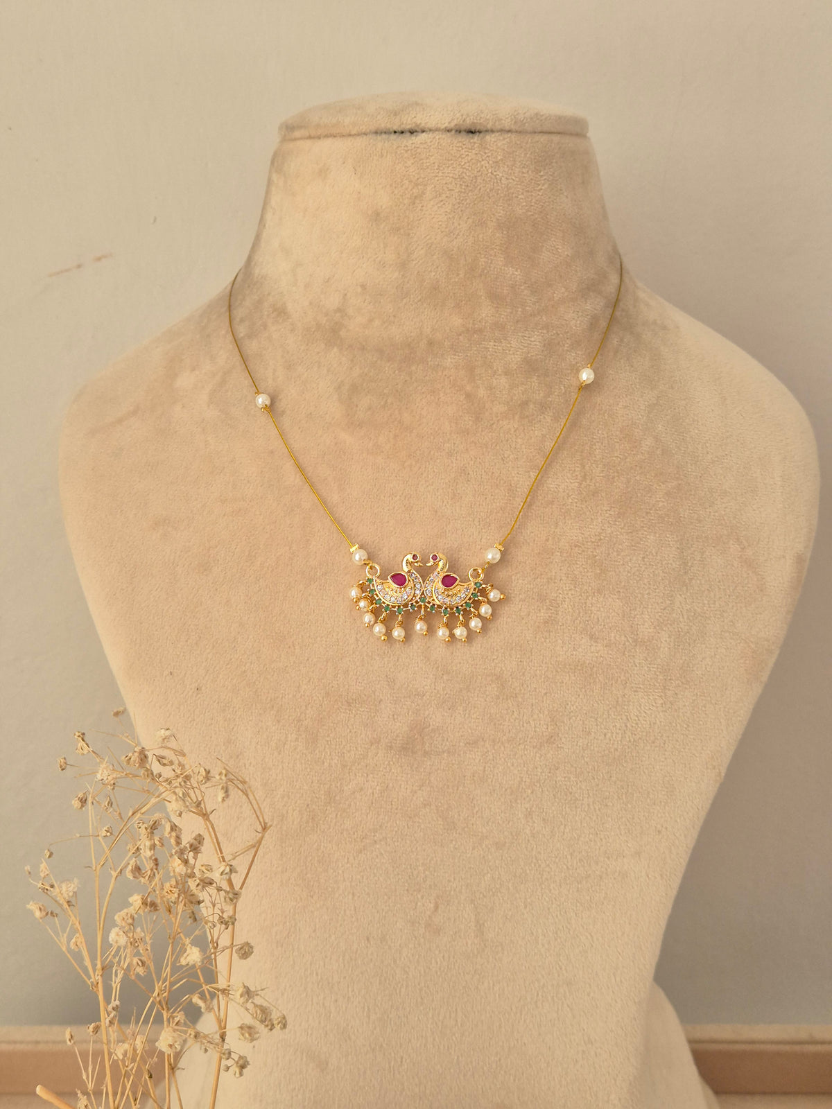 Front view of a traditional antique gold choker set featuring floral and paisley motifs, ruby-pink stones, dangling bead accents, and matching stud earrings