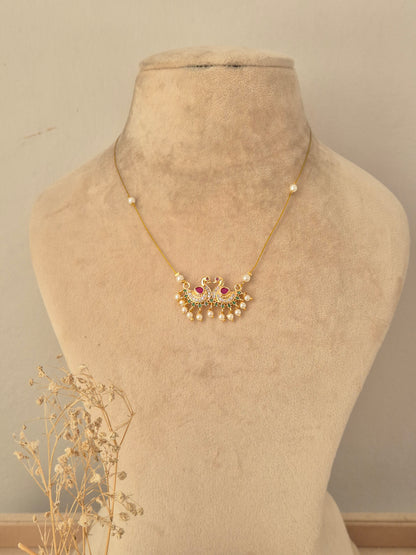 Front view of a traditional antique gold choker set featuring floral and paisley motifs, ruby-pink stones, dangling bead accents, and matching stud earrings