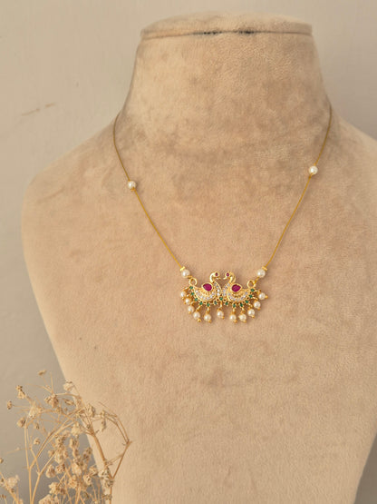 Detailed view of an antique gold choker necklace with pearl clusters and ruby-pink drop stones, alongside matching stud earrings